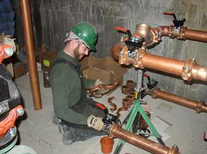Plumber in North Miami Beach installs new copper piping in a warehouse